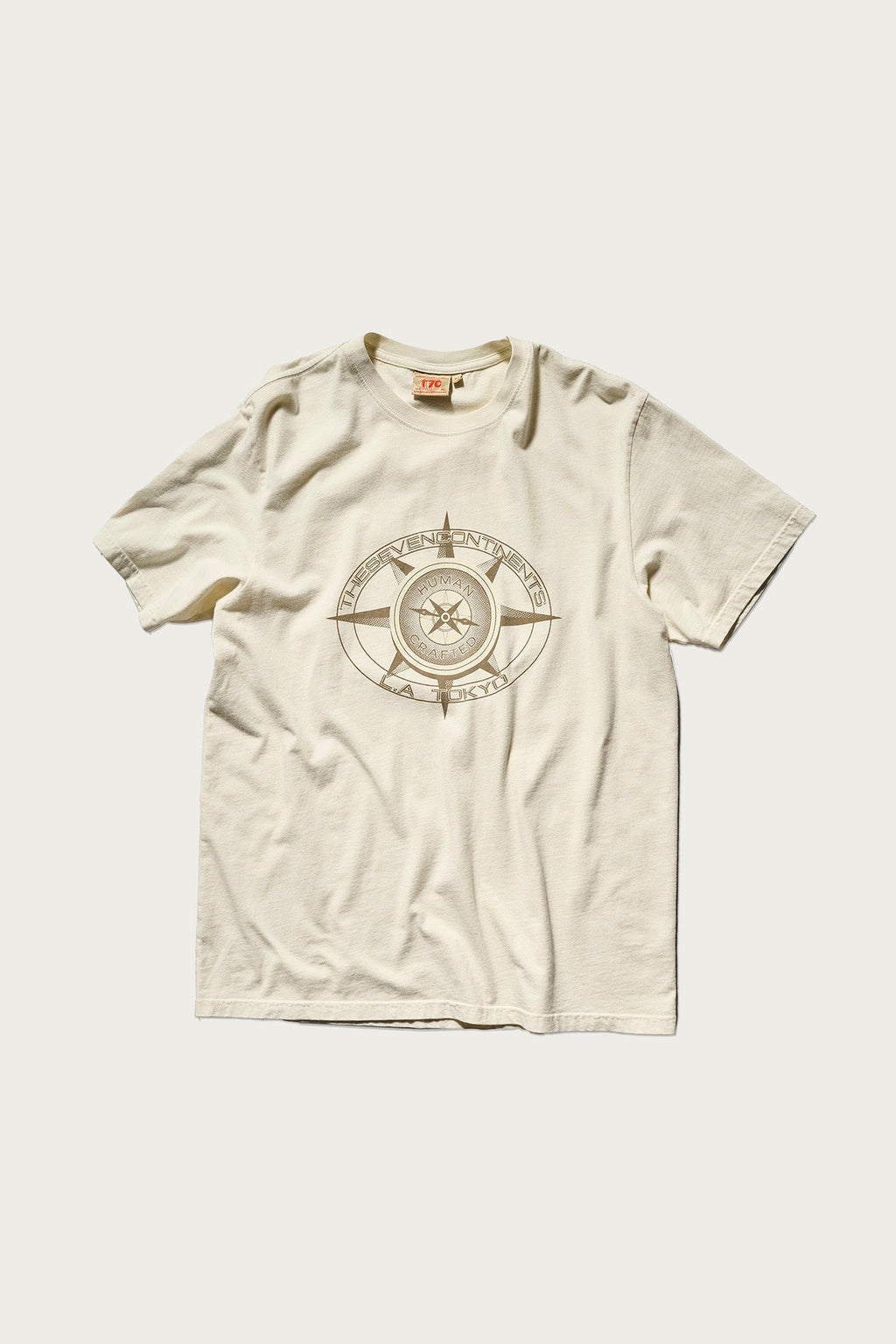 The PRE-ORDER: THE KNOXS TEE WITH MERIDIAN PRINT by T7C is a cream short-sleeve round-neck shirt featuring a bold, circular compass-inspired graphic with a star at the center of the chest.