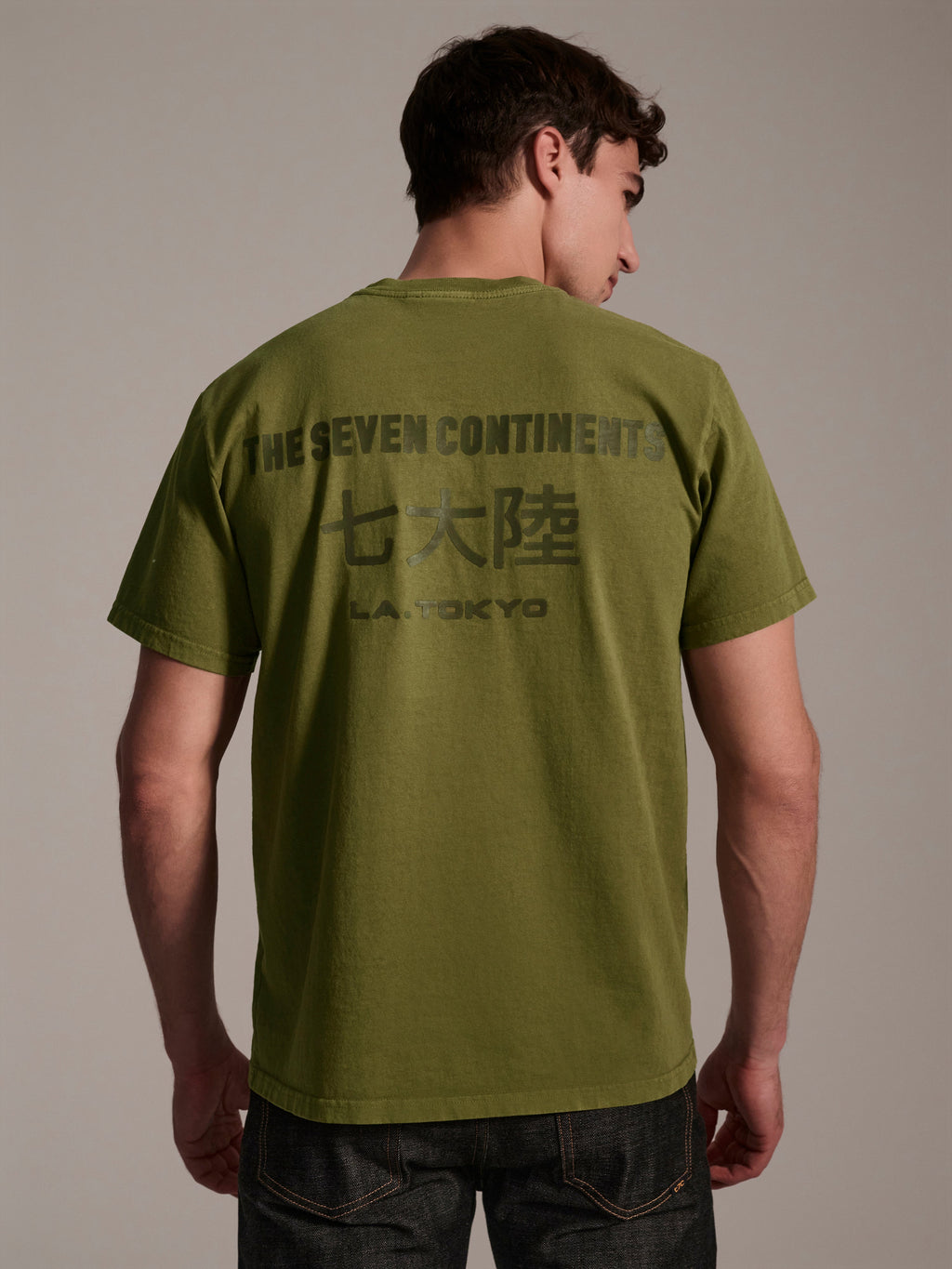 A back image of male model wearing a olive t-shirt with a logo detail